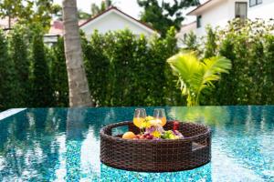 a basket of fruit and wine glasses on a table next to a pool at Buddha Bliss Luxury Villa in Ban Madua Wan