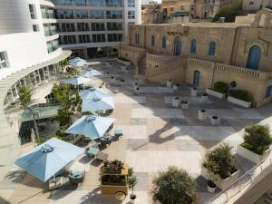 an outdoor patio with blue umbrellas and tables at Hyatt Regency Malta in St. Julianʼs