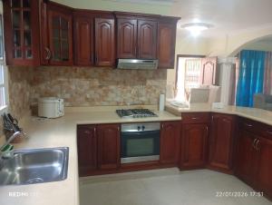 a kitchen with wooden cabinets and a stove top oven at Casa vacanza, Mendosa in Bayaguana