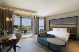 a hotel room with a bed and a couch and a desk at Hyatt Regency Malta in St. Julianʼs