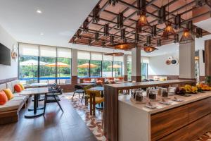 a restaurant with tables and chairs and windows at Hyatt Place Merida/ Via Montejo in Mérida