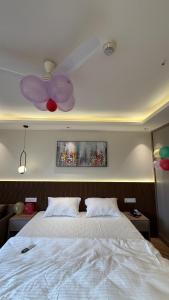 a bedroom with a white bed and a ceiling fan at Cozy haven in Greater Noida