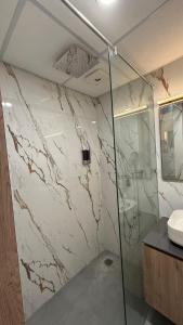 a bathroom with a glass shower and a sink at Cozy haven in Greater Noida +2 photos