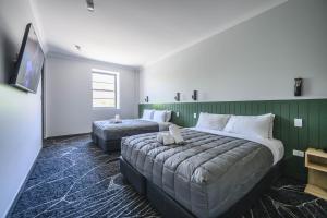 a hotel room with two beds and a flat screen tv at Belmore Hotel Maitland in Maitland