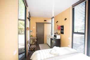 a bedroom with a bed and a kitchen with a window at Organic Farm Stay by Tiny Away in Numurkah