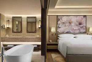 a bedroom with a bed and a bathroom with a sink at Renaissance Goa Hotel in Goa