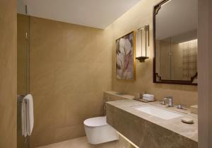 a bathroom with a sink and a toilet and a mirror at Renaissance Goa Hotel in Goa