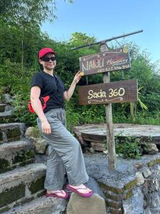 a man is standing in front of a sign at Sada 360 Nanu Homestay in Sembalun Lawang