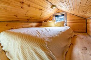 a bed in a log cabin with a window at Deep Creek Sunset by Tiny Away in Romsey +11 photos