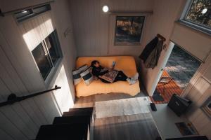 a woman sitting on a couch in a tiny house at Raintree Farmstay by Tiny Away in Sarsfield