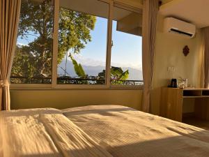 a bedroom with a bed and a large window at Superview Lodge - Family-Run, Himalayan Sunrise in Pokhara