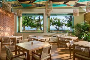 a restaurant with tables and chairs and windows at Stay Ceylon - Weligama in Weligama