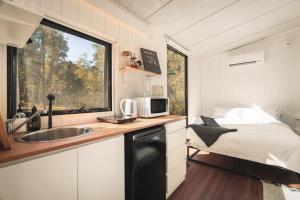 a kitchen with a sink and a bed in a tiny house at Mirror Reflections by Tiny Away in Tamborine