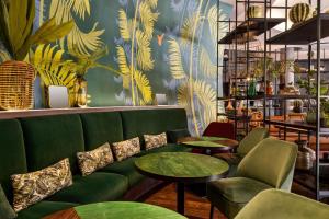 a green couch and tables in a room with plants at Vienna House by Wyndham Andel's Cracow in Krakow