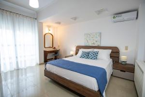 a bedroom with a large bed with a blue blanket at Seascape Village - Spacious 3-Bed Apartment with Private Garden and Parking in Kalithies
