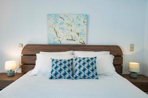 a bed with white pillows and a painting above it at Seascape Village - Spacious 3-Bed Apartment with Private Garden and Parking in Kalithies