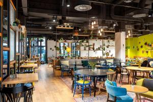 a restaurant with tables and chairs and a bar at Sunday Hotel Leipzig in Leipzig