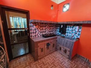a small kitchen with orange walls and a counter top at Abhishek Homestay in Dum Duma