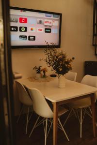 a dining room table with chairs and a tv on the wall at Cudomki nad jeziorem Krzywym in Piecki