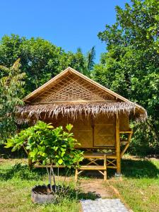a hut with a thatched roof in a field at Tarzan Bamboo hut in Khao Sok National Park