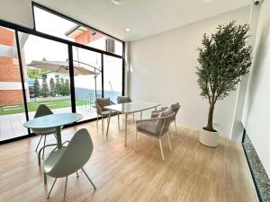 a dining room with tables and chairs and a potted tree at Whiteinn - ไวท์อินน์ in Nonthaburi +8 photos