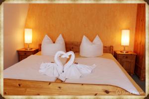 ein Bett mit zwei Handtüchern in Herzform in der Unterkunft Hotel Pränzkow in Zwickau