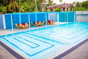 a swimming pool with tables and chairs in it at Hotel Friendstar in Minuwangoda