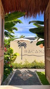 an entrance to a resort with a sign with a palm tree at Bacana Bungalows in Uluwatu +47 photos