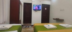 a room with two beds and a tv on a wall at Royal Green Residency Chennai Airport in Chennai
