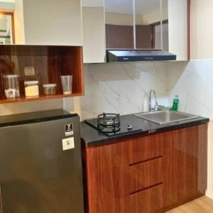 a kitchen with a sink and a refrigerator at Delf Apartement Cpi Mewah By Selfiyani in Makassar