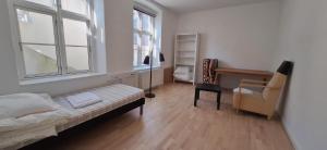 a bedroom with a bed and a chair and two windows at Private Room in a shared apartment in Odense +7 photos