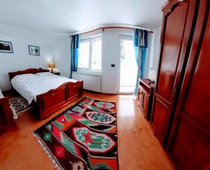 a bedroom with a bed and a window and a rug at Pensiunea Casa Bradet in Statjunea Borsa