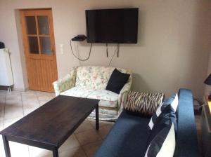 ein Wohnzimmer mit einem Sofa und einem TV an der Wand in der Unterkunft Ferienwohnung Am Igelsberg in Saal