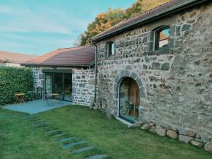 a stone building with a yard next to a house at Le Moulin des Puys in Orcines