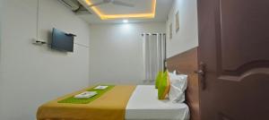 a small bedroom with a bed with a yellow blanket at Hotel Royal Green Inn in Chennai