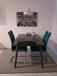 a dining room table with two chairs and aendant light at Gästewohnung in Parkstetten bei Straubing in Parkstetten