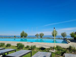 a swimming pool with picnic tables and the ocean in the background at Herberge Seeperle Bistro Rorschach in Rorschach +11 photos
