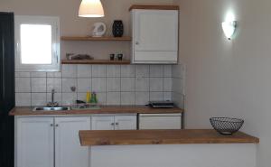 a kitchen with white cabinets and a sink at Toni´s Guesthouse in Kavos