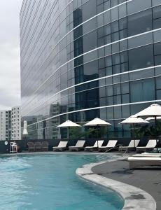 a pool with chairs and umbrellas in front of a building at 枫枫枫 in Hong Kong