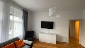 a living room with a couch and a tv on a wall at Junior Suite Apartment Eleven in Graz