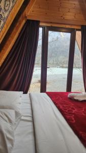 a bed in a room with a large window at Ecohouse Machakhela in Machakhela