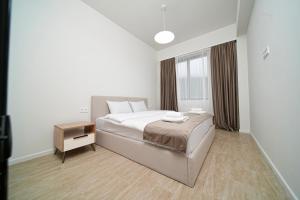 a white bedroom with a bed and a night stand at Verinn Apart Hotel in Dilijan