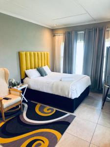 a bedroom with a king sized bed and a chair at Elegant guest house in Matsapha