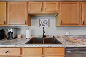 a kitchen with a sink and wooden cabinets at Beachside Condo w Stunning Lake Views in Sheboygan