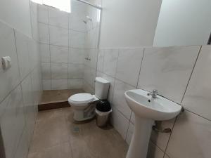 a white bathroom with a toilet and a sink at Villa Gabriel Hotel in Piura