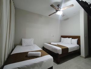 two beds in a room with a ceiling fan at Villa Gabriel Hotel in Piura +16 photos