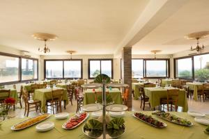 a dining room with tables and chairs and windows at Triscinamare Hotel Residence in Triscina