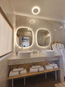 a bathroom with two sinks and two mirrors at Modular Bungalows With Heated Pool Artemis Greece in Artemida