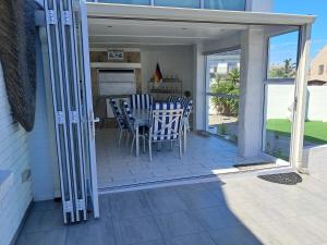 a patio with chairs and a table on a porch at Beach Style Cottage in Langebaan