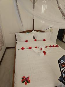 a white bed with red flowers on it at Upole HOTEL in Nungwi